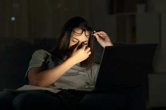 Fatigued woman using laptop at night
