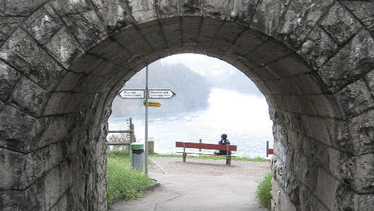person sittin on a bench at the end of a tunnel with signposts pointing left or right