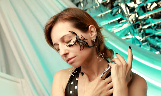a scorpion on a woman's face, her eyes are closed