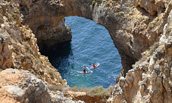 two kayaks on the water passing under a stone arch