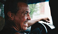 a joyful smiling man at the wheel of a car